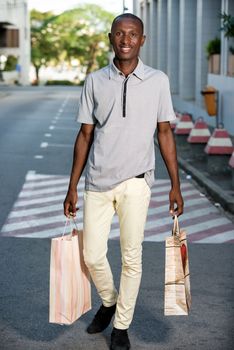 Portrait of happy man with shopping bags walking down the street after shopping in town.