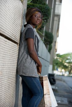 happy woman standing outside leaning against wall at with shopping bags in the street