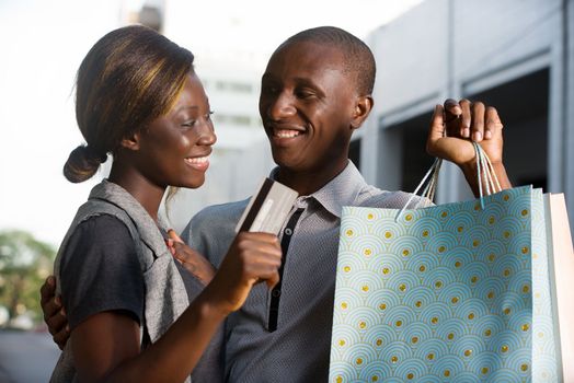 young happy couple holds shopping bags with a credit card out.Concept of shopping and free time.