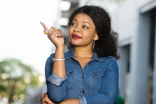 Cheerful girl wearing blue jeans shirt pointing a place with hand in the street
