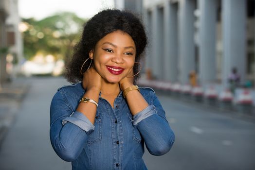 Young happy and free woman standing in the street laying hands on the neck and looking at the camera