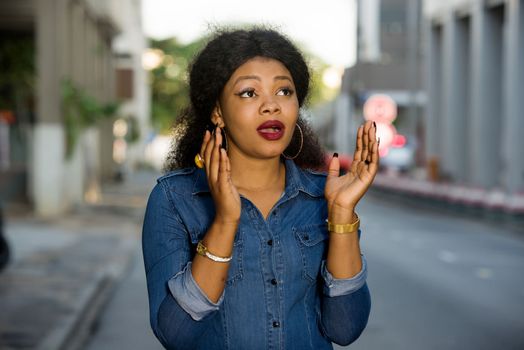 Young woman surprised in the street because of some news. She walks in the street and has the good mood