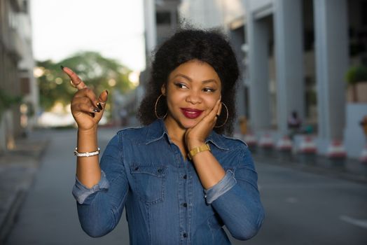 Cheerful girl wearing blue jeans shirt pointing a place with hand in the street