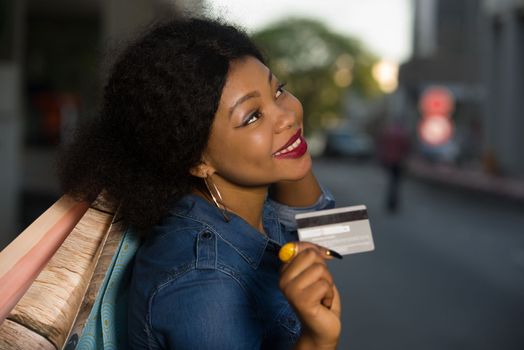 Portrait of smiling woman with a credit card and shopping bags in a hand in town