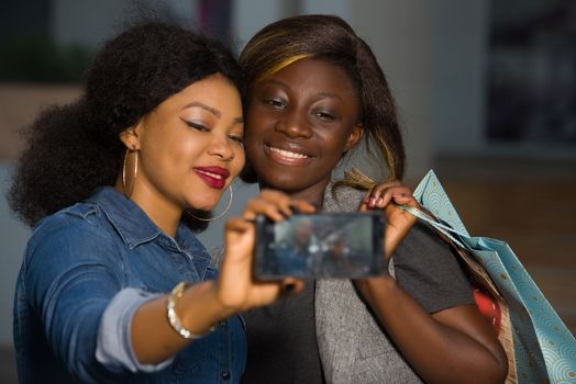 young girls standing in the air looking to photograph themselves with mobile phone smiling.