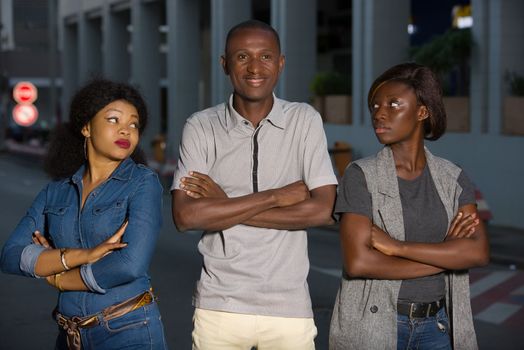 two jealous women are fighting a man.Divorce of a couple outdoors in the city man standing between two angry girlfriends is watching the camera