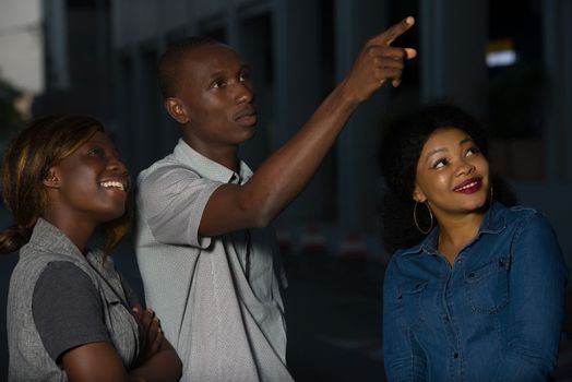 Group of young people walking on the street. three friends having fun and talking outdoors.Young man showing something