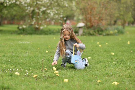 Girl collects the eggs in a basket Easter