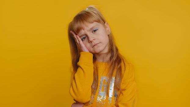 Displeased child girl kid rubbing temples to cure headache problem, suffering from tension, migraine, stress, grimacing in pain tired from study education. Little toddler children on yellow background
