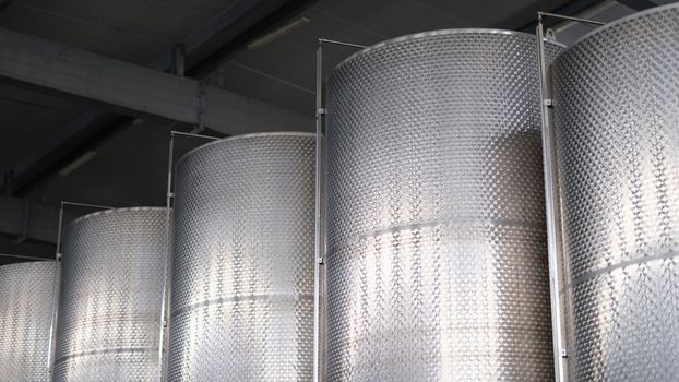 Steel tanks for storing alcohol in winery closeup. Modern brewery with brew kettles pipes and stainless steel tanks.