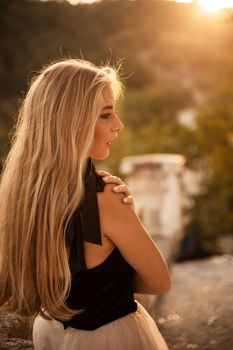 Blonde long hair, nature summer happy adult girl with long blond hair developing in the wind in nature. Dressed in a black top, white skirt