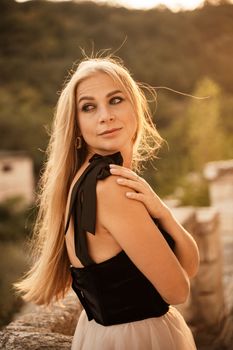 Blonde long hair, nature summer happy adult girl with long blond hair developing in the wind in nature. Dressed in a black top, white skirt