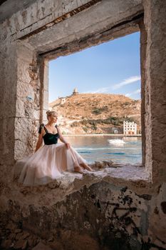 Side view portrait of a relaxed woman breathing fresh air at the seaside. She stands on the window in the old building