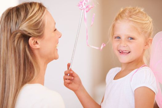 Shell grant her mum any wish she wants. Portrait of a smiling girl dressed up as a fairy and holding a wand standing infront of her mother