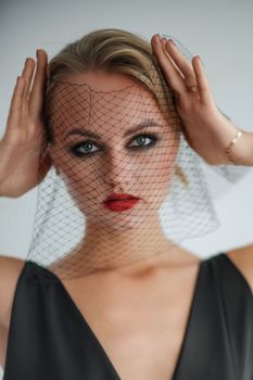 Portrait of a beautiful blonde woman with a veil in a black dress.