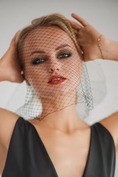 Portrait of a beautiful blonde woman with a veil in a black dress.