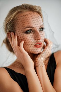 Portrait of a beautiful blonde woman with a veil in a black dress.