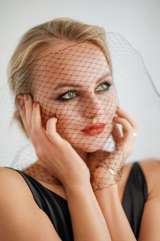 Portrait of a beautiful blonde woman with a veil in a black dress.
