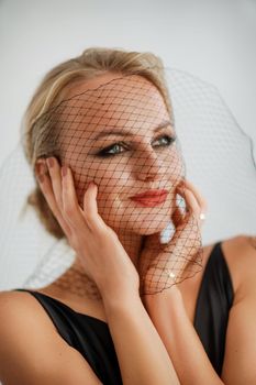 Portrait of a beautiful blonde woman with a veil in a black dress.