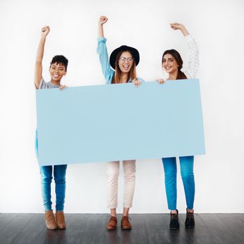 Stand up for something you believe in. Studio shot of a group of young women holding a blank placard and cheering against a white background