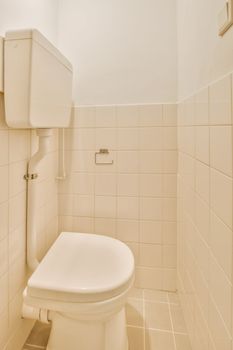 a white toilet in a small bathroom with tiled walls and tile flooring on the wall behind it is an open door
