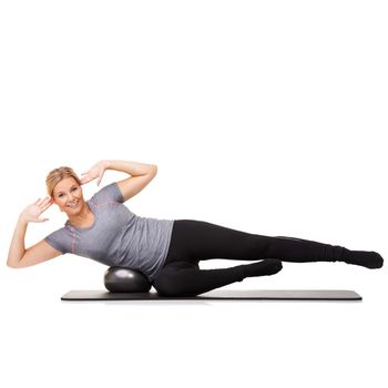 Exercise gives me energy. A young woman lying on her exercise ball and working her obliques