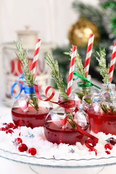 Gin with tonic and cranberry juice. The cocktail is full of festive Christmas flavors. Served in transparent bowls with a branch of rosemary.