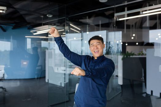 Happy young male student, freelancer dancing in office, on campus. Celebrating victory, passing an exam, enrolling in a university, going to work. A successful deal, financial success, work break.