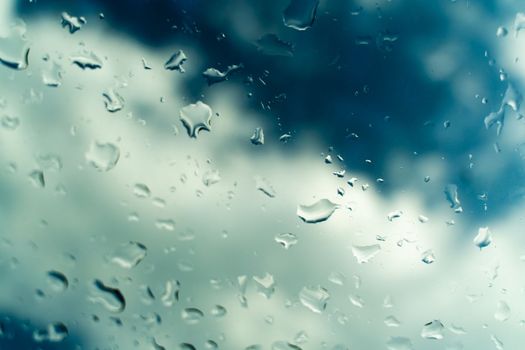 Raindrops on glass against blue sky. Window view background screensaver. Place for text banner.