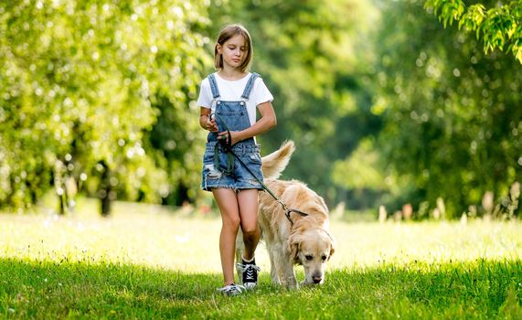 Cute little girl with lovely dog walking on summer meadow