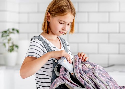 Preteen girl preparing backpack for school class lessons at home. Female pupil with schoolbag