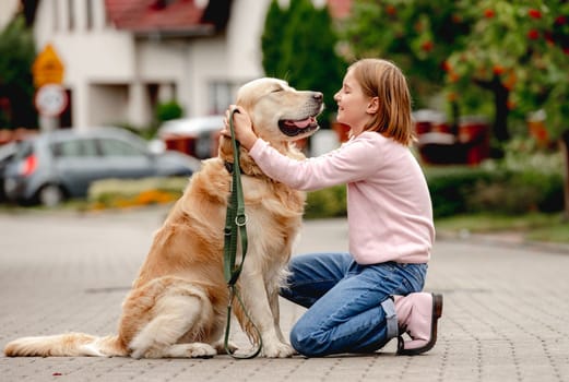 Preteen girl wear on golden retriever dog lace outdoors. Pretty kid child with purebred pet doggy walking at street