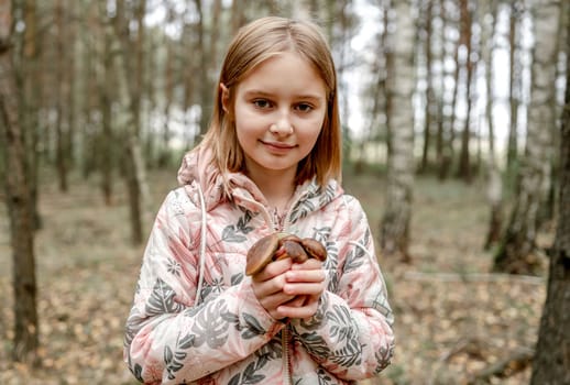 cute girl holding Boletus Edulis Mushroom in hands on the background of autumn forest