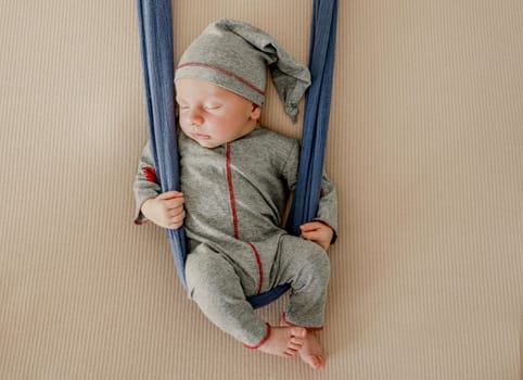 Newborn baby boy sleeping with knitted heart toy during studio photoshoot. Adorable infant child kid sleeping wearing hat and costume