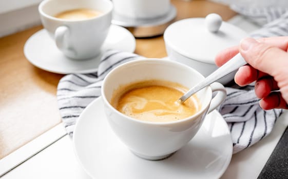 Girl stirs sugar in a cup of coffee. Close-up