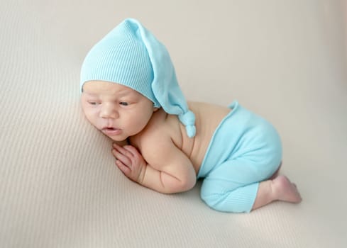 Newborn baby boy wearing knitted pants and hat sleeping on his tummy. Infant child kid napping