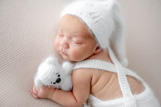 Newborn baby boy wearing knitted pants and hat sleeping on his tummy. Infant child kid napping and holding hand under cheek