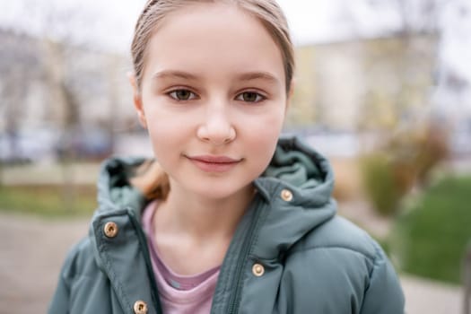 Preteen girl street portrait in city with blurred background. Cute female child kid outdoors at autumn time