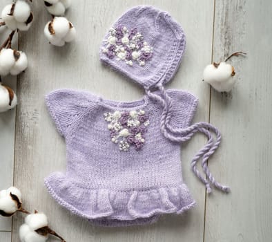 knitted newborn baby clothes composed on a wood table