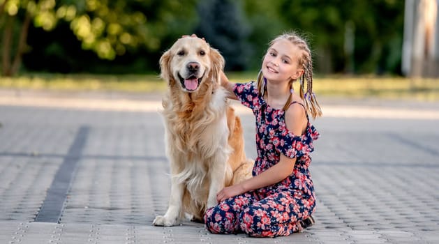 Preteen girl and her golden retriever dog on lace looking at camera. Female child kid with a purebred labrador doggy pet