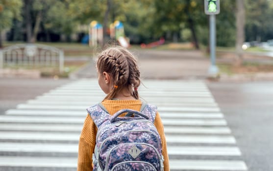 School girl with backpack crossed the road. Pretty female child kid portrait from back outdoors