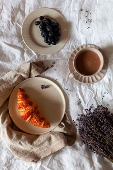 traditional french breakfast of a croissant, grapes and hot chocolate, overhead photo