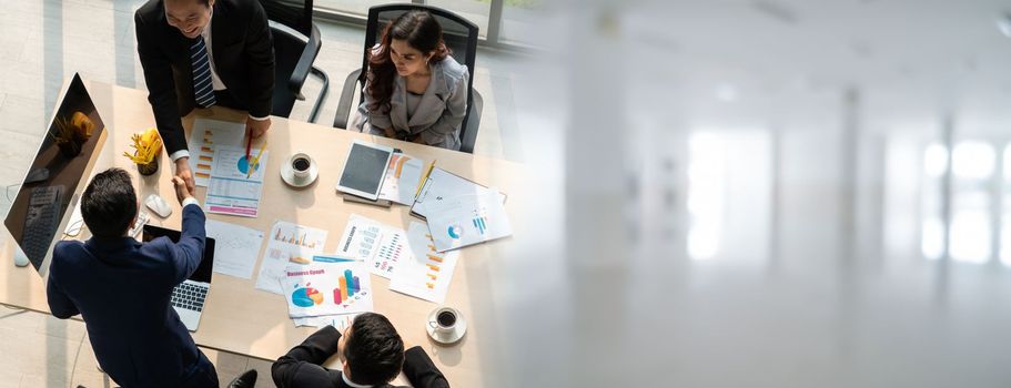 Group business people handshake at meeting table in widen view in office together with confident shot from top view . Young businessman and businesswoman workers express agreement of investment deal.