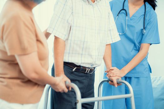 Contented senior man was helped on folding walking by his wife and caregiver. Recuperation for elderly, seniors care, nursing home.