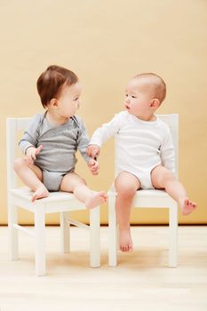 Making new friends. Adorable shot of two cute babies sitting on chairs and smiling at each other