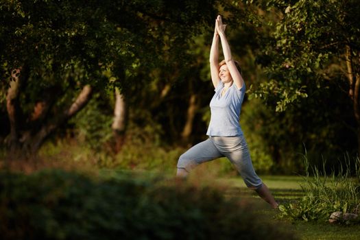 Yoga keeps her glowing. an attractive woman doing yoga in the outdoors