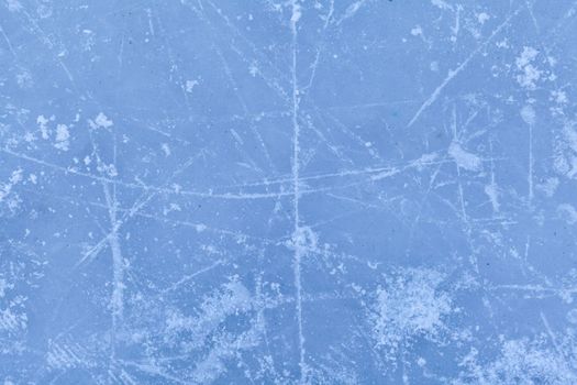 Empty ice rink with skate marks after the session outdoor. skating ice rink texture covered with snow in daylight. Close up of blue ice rink floor, copy space