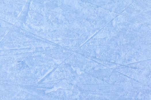 Empty ice rink with skate marks after the session outdoor. skating ice rink texture covered with snow in daylight. Close up of blue ice rink floor, copy space