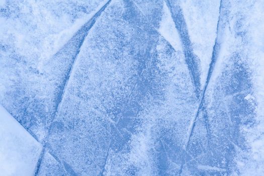 Empty ice rink with skate marks after the session outdoor. skating ice rink texture covered with snow in daylight. Close up of blue ice rink floor, copy space