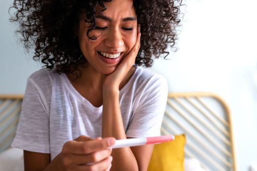 Close up of happy young African American woman checking pregnancy test. Family concept.